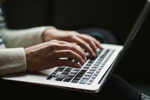 Des mains en train de taper sur la clavier d'un ordinateur portable