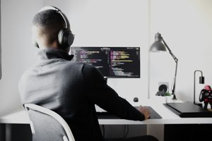 Un homme assi à son bureau devant un écran d'ordinateur avec du code affiché