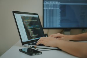 Un individu utilise un ordinateur portable, les doigts sur le clavier.