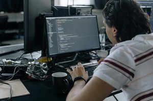 Un homme est assis devant un ordinateur avec du code à l'écran